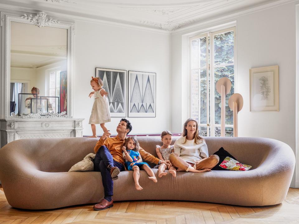 Benjamin Paulin and Alice Lemoine, with daughters Irene and Diane and a friend, on a Pierre Paulin Big C sofa in their Paris living room; artworks by Verner Panton.