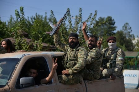 Members of Syrian National Army, known as Free Syrian Army, wave as they drive to cross into Syria near the Turkish border town of Ceylanpinar