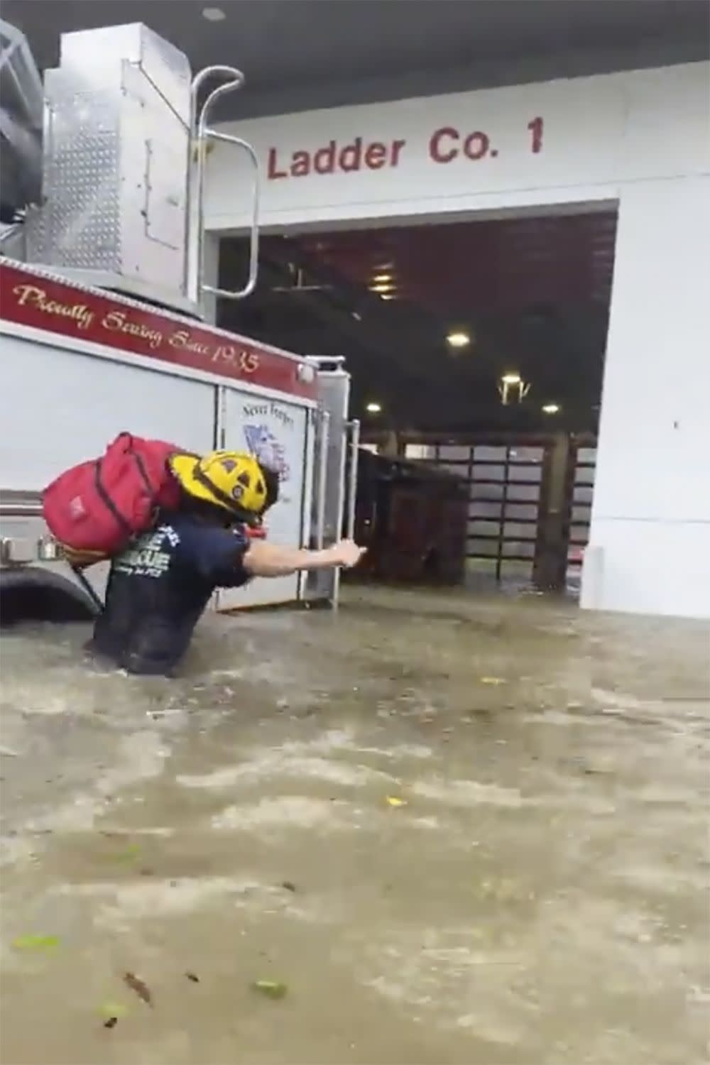 This image provided by the Naples Fire Rescue Department shows a firefighter carrying gear in water from the storm surge from Hurricane Ian on Wednesday, Sept. 28, 2022 in Naples, Fla.  