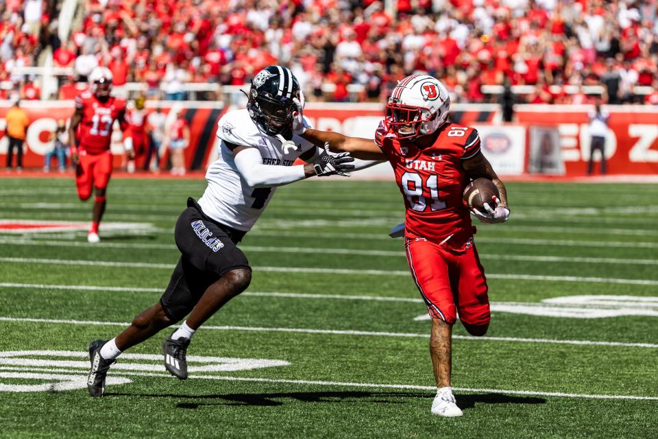 Utah wide receiver Mikey Matthews runs the ball down the field with Weber State’s Abraham Williams (4) on defense.