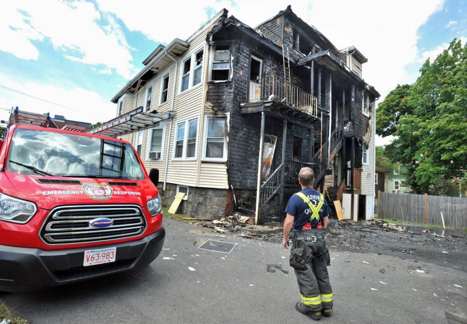 A firefighter looks at the charred remains of a rooming house at 100 Bigelow St. in Quincy that was destroyed by a multi-alarm fire. Several tenants were rescued and another jumped out a window, Sunday, July 31, 2022.