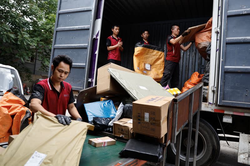 Delivery workers unload packages from a truck ahead of the "618" shopping festival, at a logistics station in Beijing