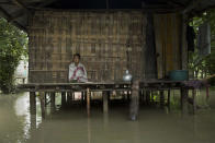 <p>An Indian Mishing tribal woman sits at her traditional hut surrounded by flood waters at Majuli, a river island east of Gauhati, northeastern Assam state, India, July 27, 2016. (Photo: Anupam Nath/AP)</p>