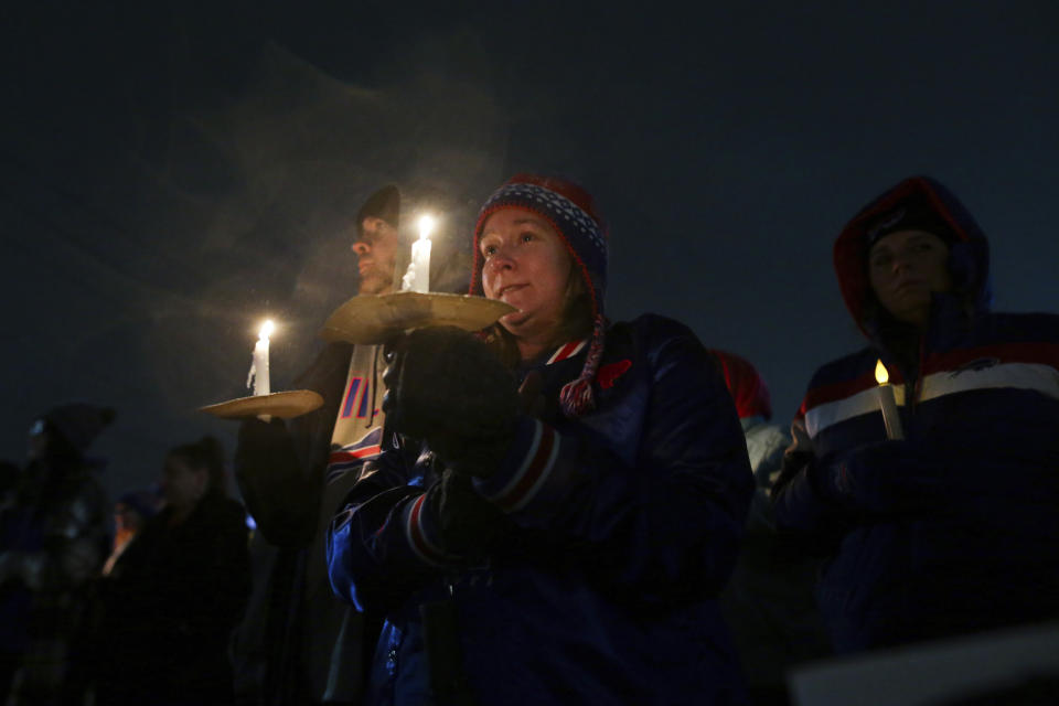 FILE - Curtis, left, and Amanda Grantham listen to speakers during a candlelight vigil for Buffalo Bills safety Damar Hamlin on Tuesday, Jan. 3, 2023, in Orchard Park, N.Y. The Buffalo Bills have been a reliable bright spot for a city that has been shaken by a racist mass shooting and back-to-back snowstorms in recent months. So when Bills safety Damar Hamlin was critically hurt in a game Monday, the city quickly looked for ways to support the team. (AP Photo/Joshua Bessex)