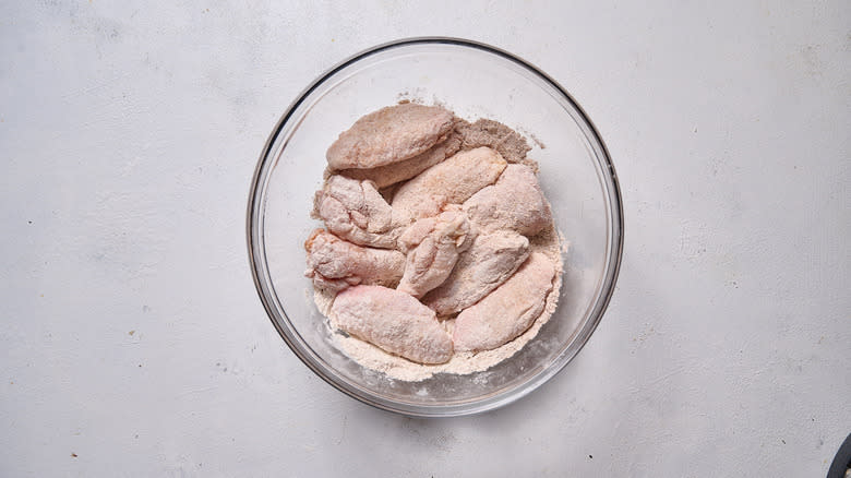 flour coated chicken in mixing bowl