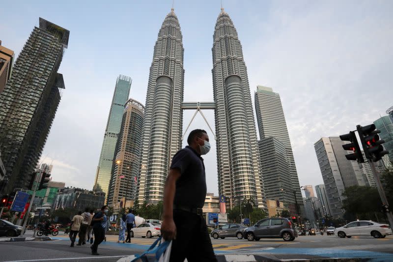 A man wearing a protective mask crosses a street in front of Petronas Twin Towers, amid the coronavirus disease (COVID-19) outbreak in Kuala Lumpur