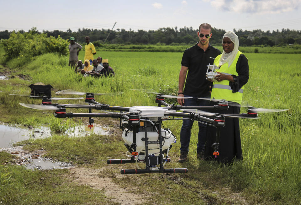 In this photo taken Thursday, Oct. 31, 2019, Eduardo Rodriguez, left, of drone manufacturer DJI, trains Khadija Ali Abdulla, right, from the State University of Zanzibar, how to fly a drone to spray the breeding grounds of malaria-carrying mosquitoes, at Cheju paddy farms in the southern Cheju region of the island of Zanzibar, Tanzania. Drones spraying a silicone-based liquid that spreads across the large expanses of stagnant water where malaria-carrying mosquitoes lay their eggs, are being tested to help fight the disease on the island of Zanzibar, off the coast of Tanzania. (AP Photo/Haroub Hussein)