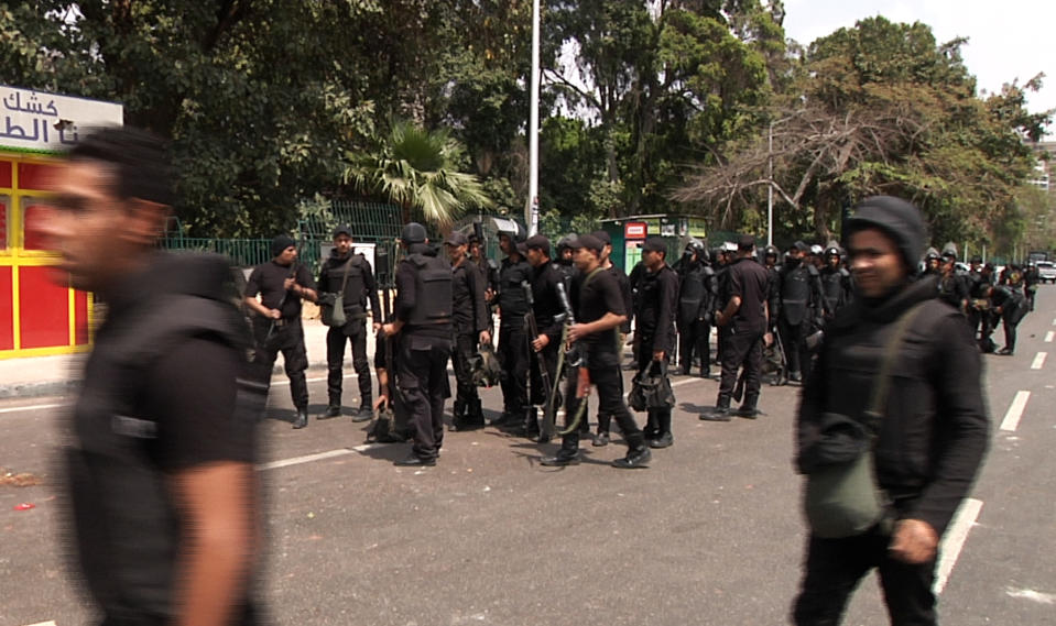 In this image taken from AP Television, Egyptian security forces inspect the scene after multiple explosions hit the area outside the main campus of Cairo University, killing at least two, in Giza, Egypt, Wednesday, April 2, 2014. The bombings targeted riot police routinely deployed at the location in anticipation of near-daily protests by students who support ousted Islamist President Mohammed Morsi and his Muslim Brotherhood group. (AP Photo/AP Video)