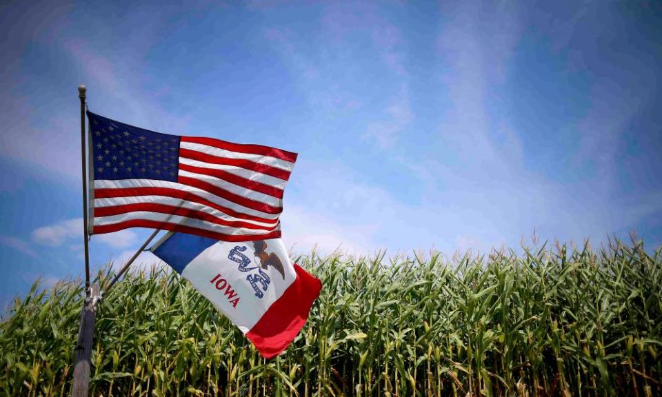 US and Iowa state flags fly next to a corn field in Grand Mound, Iowa.