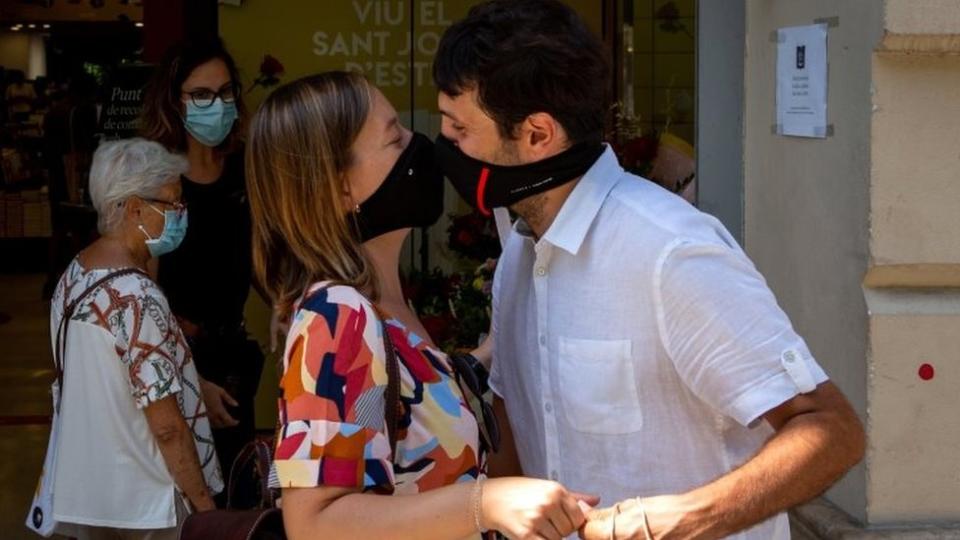 Una pareja se besa con mascarillas puestas