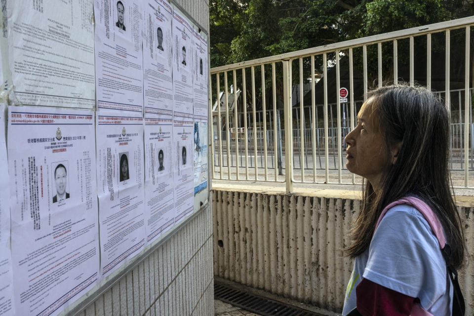 FILE - A pedestrian looks at the police reward notices for the arrest warrants issued for eight pro-democracy activists living in the United States, Britain, Canada and Australia for alleged national security offenses in Hong Kong, Friday, July 14, 2023. Hong Kong police accused five activists based overseas Thursday, Dec. 14, 2023 of breaching a harsh national security law imposed by Beijing and offered rewards of 1 million Hong Kong dollars ($128,000) for information leading to each of their arrests. In July, Hong Kong warned eight other activists who now live abroad that they would be pursued for life under bounties put on them. It was the first such use under the security law, and the authorities’ announcement drew criticism from Western governments. (AP Photo/Louise Delmotte, File)