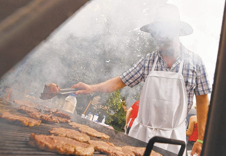 Smoke rises off the grill as Erik Bertermann flips prime rib sandwiches at the Janko's Little Zagreb booth at the Taste of Bloomington festival in Showers Plaza Saturday, June 22, 2019. (Rich Janzaruk / Herald-Times)