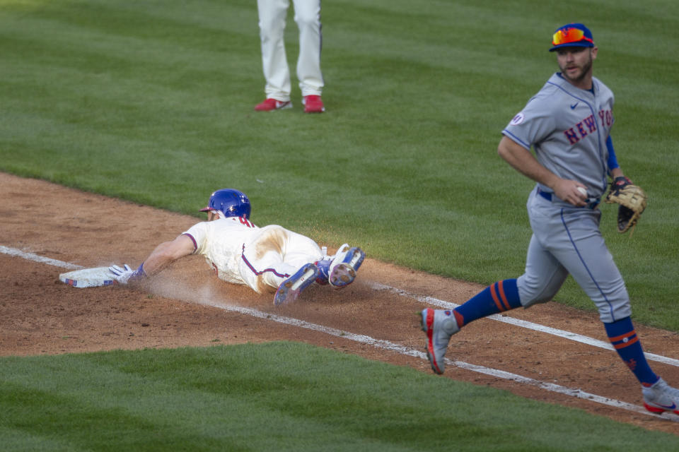 Philadelphia Phillies' Bryce Harper slides into first base on a bunt before New York Mets first baseman Pete Alonso could make the tag during the fifth inning of a baseball game Wednesday, April 7, 2021, in Philadelphia. (AP Photo/Laurence Kesterson)