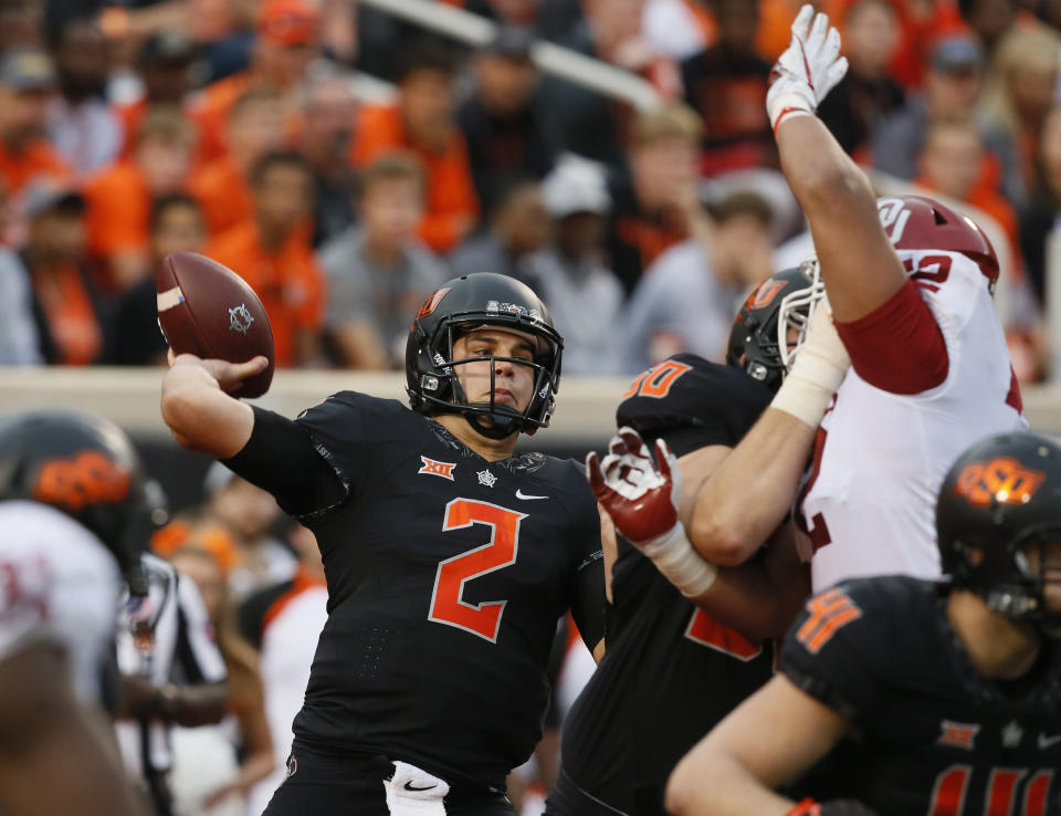 FILE - Oklahoma State quarterback Mason Rudolph (2) looks to pass under pressure in the second half of an NCAA college football game against Oklahoma in Stillwater, Okla., Nov. 4, 2017. Oklahoma and Oklahoma State will meet on Saturday for the final time before Oklahoma leaves the Big 12 for the Southeastern Conference. (AP Photo/Sue Ogrocki, File)