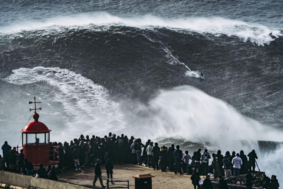 Crowds gather at Nazaré, Portugal to watch surfers take on immense waves.