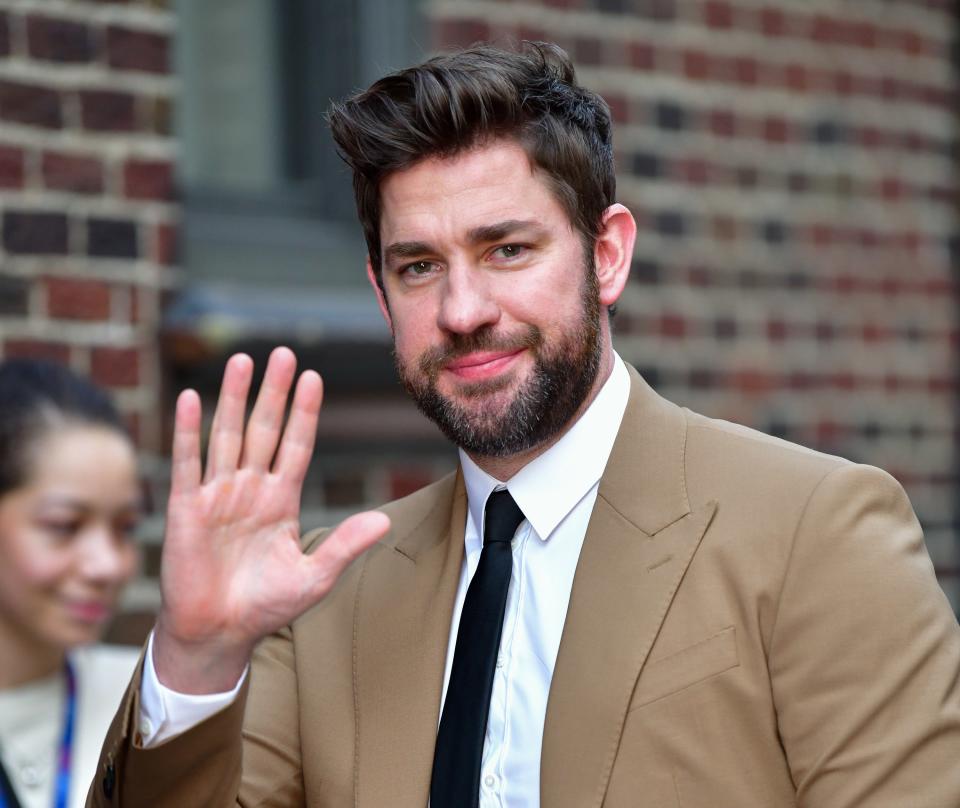 Photo of John Krasinski smiling and waving at the camera