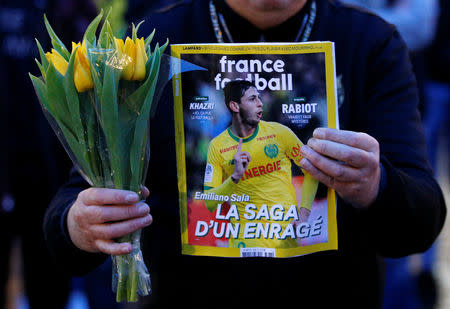 A man holds a sports magazine and yellow tulips as fans gather in the Nantes city center after news that newly-signed Cardiff City soccer player Emiliano Sala was missing after the light aircraft he was travelling in disappeared between France and England