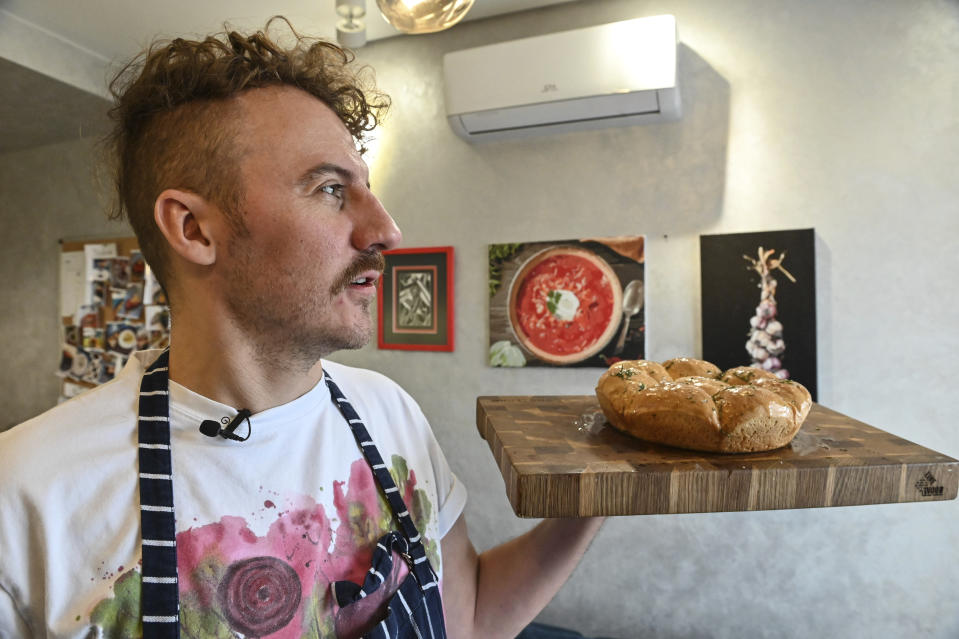 Ukrainian chef Ievgen Klopotenko poses with a tray of Pampushky bread in his kitchen in Kyiv, Ukraine on Feb. 5, 2023. Klopotenko has been outspoken during the Russian invasion in promoting national dishes, especially borsch, as a way of establishing a definite identity for Ukraine. (AP Photo/Chris Warde-Jones)