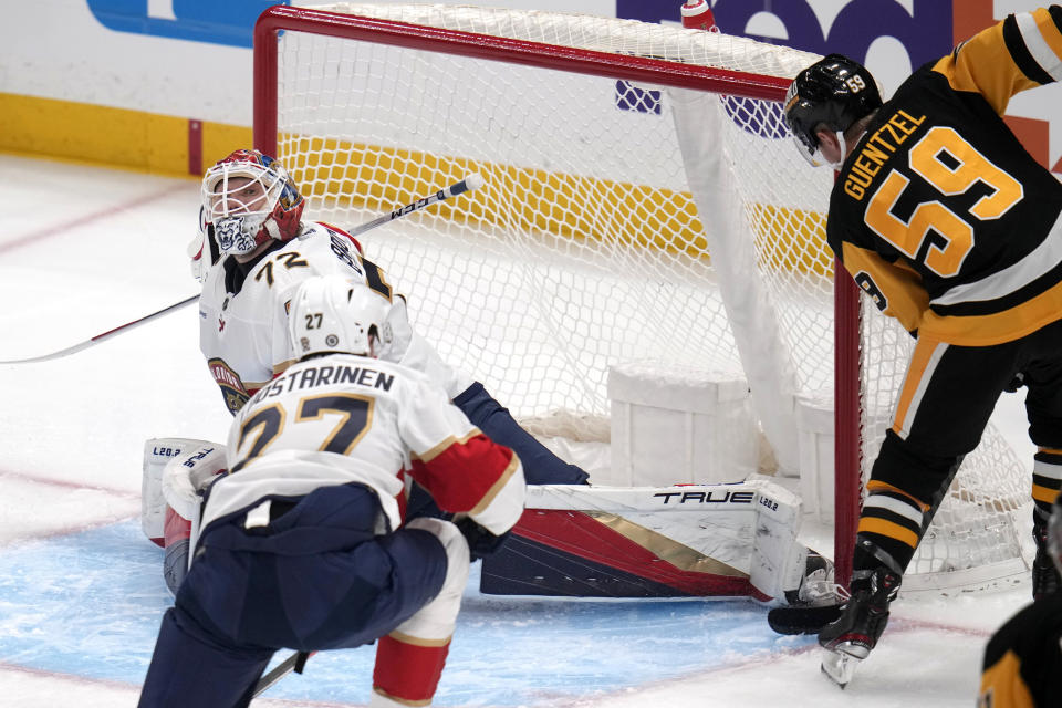 Pittsburgh Penguins' Jake Guentzel (59) gets the puck past the skate of Florida Panthers goaltender Sergei Bobrovsky (72) for a goal with Eetu Luostarinen (27) defending during the first period of an NHL hockey game in Pittsburgh, Friday, Jan. 26, 2024. (AP Photo/Gene J. Puskar)