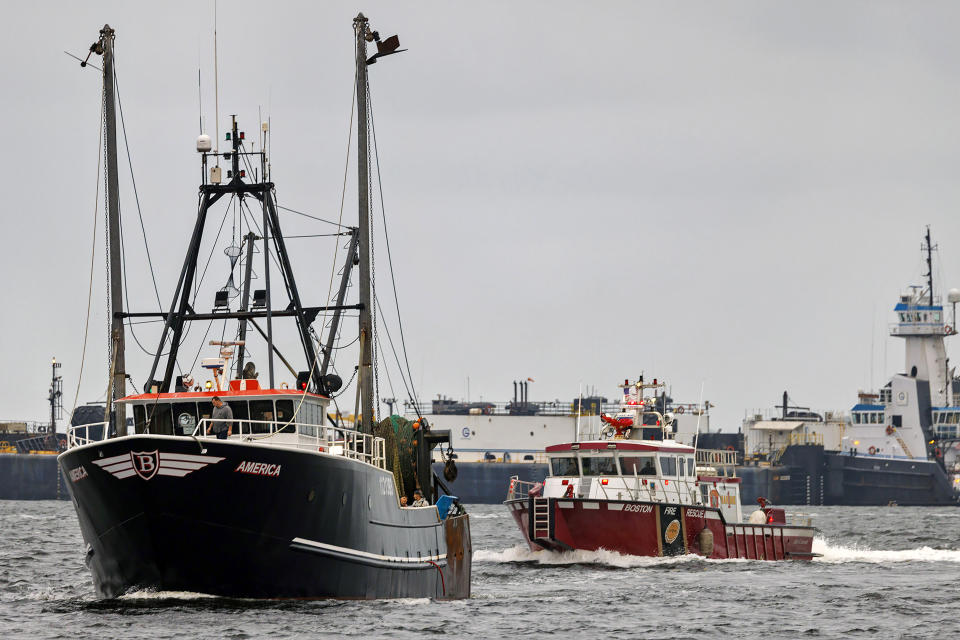 In a photo provided by NBC10 TV commercial fishing boat America, left, sails toward Boston, Tuesday, Sept. 26, 2023. Officials say the crew of the fishing boat recovered a man who had fallen overboard from the tanker MTM Dublin early Tuesday and began CPR. The America found the crew member after being the first vessel on the scene, said a Coast Guard spokesperson. The mayday from the tanker MTM Dublin went out shortly after 4:30 a.m. The man’s condition is not known. (NBC10 via AP)