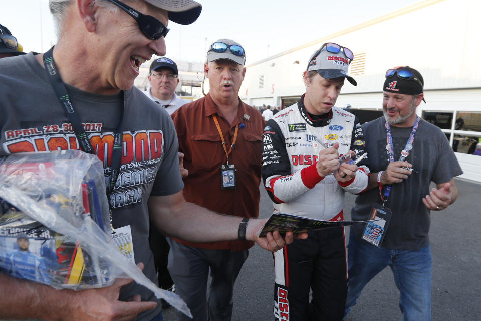 Brad Keselowski, second from right, gives autographs after winning the pole for a NASCAR Monster Energy Cup auto race at Richmond Raceway in Richmond, Va., Friday, Sept. 20, 2019. (AP Photo/Steve Helber)