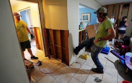 Ben LeDoux, cousin of the homeowner, kicks a hole in Hurricane Harvey flood damaged drywall in a home in southwestern Houston, Texas, U.S. September 2, 2017. REUTERS/Rick Wilking