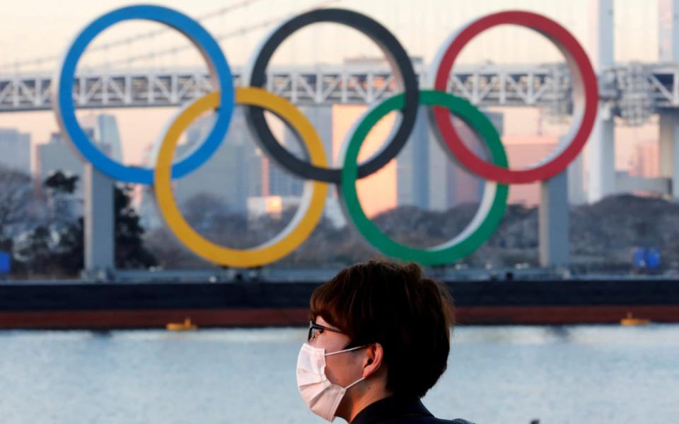 A man wears a protective mask amid the coronavirus disease (COVID-19) outbreak, in front of giant Olympic rings in Tokyo - Reuters