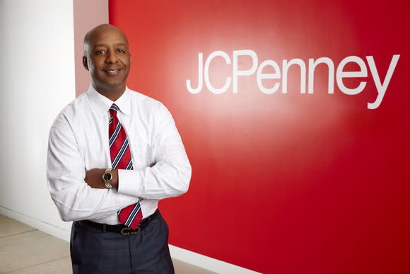 J.C. Penney CEO Marvin Ellison in front of a red wall with the Penney logo printed in white on it.