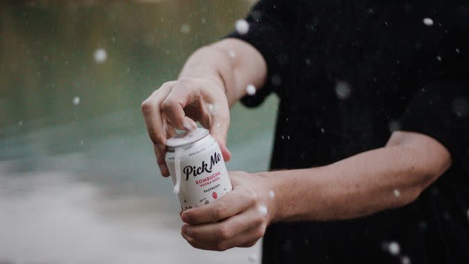 man opens kombucha vodka soda can.