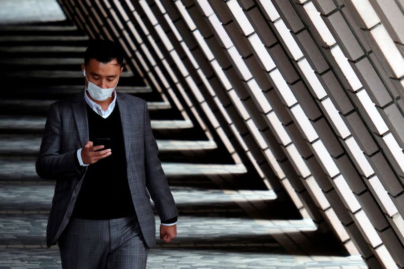 FILE PHOTO: A man wears a protective mask as he walks at a tourist spot, following the outbreak of the novel coronavirus, at Tsim Sha Tsui district in Hong Kong