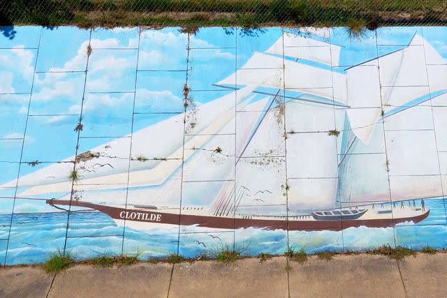 <p>Oliver Dorgan/Courtesy of Visit Mobile</p> A mural of the Clotilda along Africatown Boulevard.