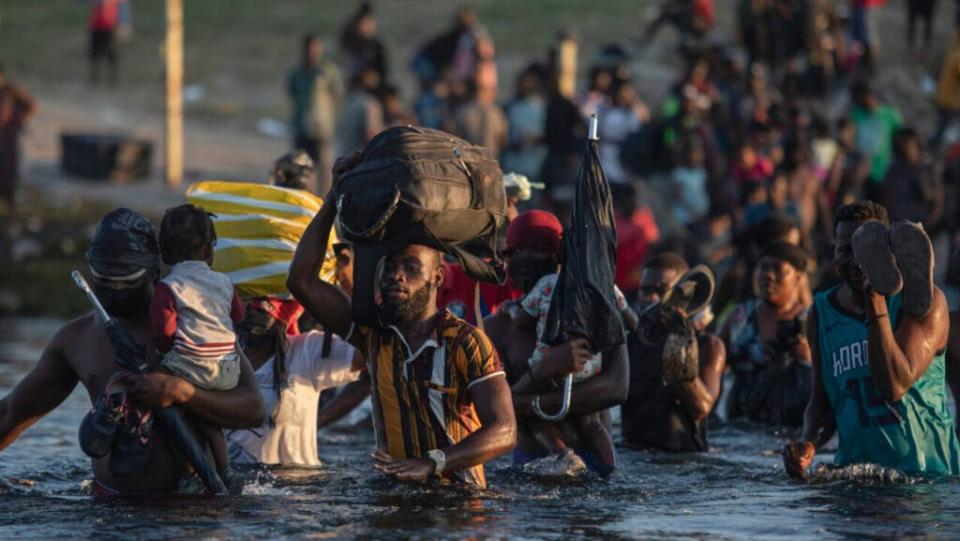 Migrants, many from Haiti, wade across the Rio Grande river from Del Rio, Texas