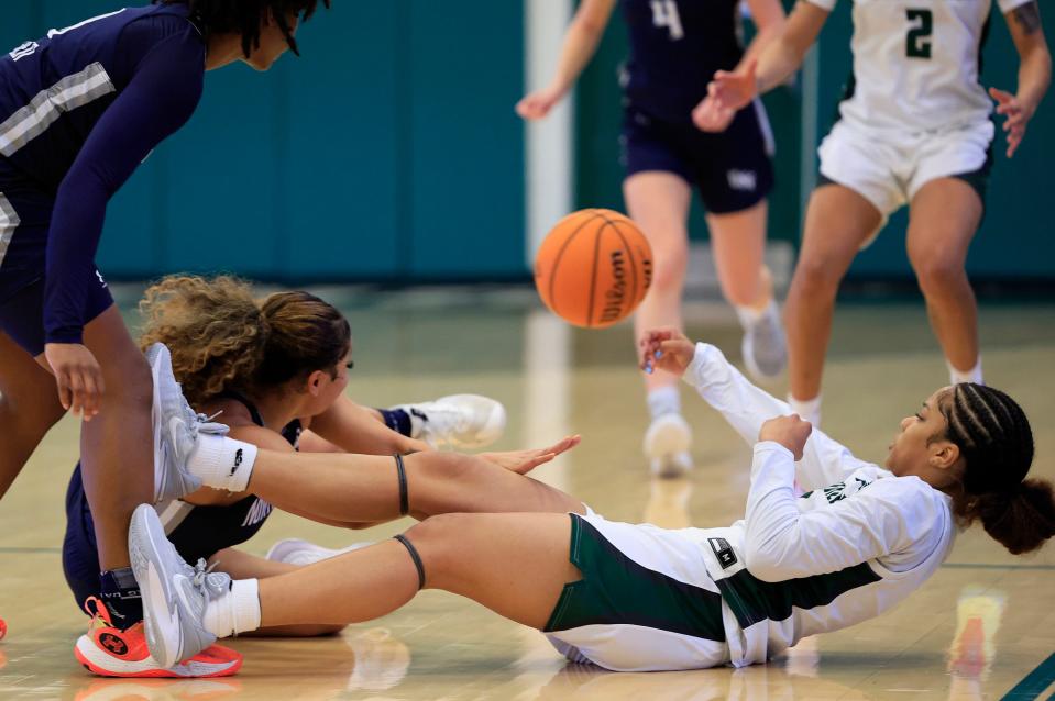 Jacksonville Dolphins guard Sana'a Garrett (3) passes from her back against North Florida Lady Ospreys guard Lyric Swann (22) during the second quarter of an NCAA women’s basketball matchup Saturday, Feb. 17, 2024 at Jacksonville University’s Swisher Gymnasium in Jacksonville, Fla. JU downed UNF 73-60.