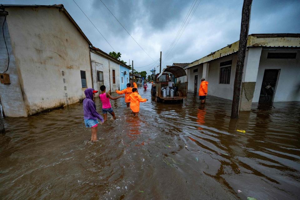 People walk through a flooded street in Batabano, Cuba (AFP via Getty Images)