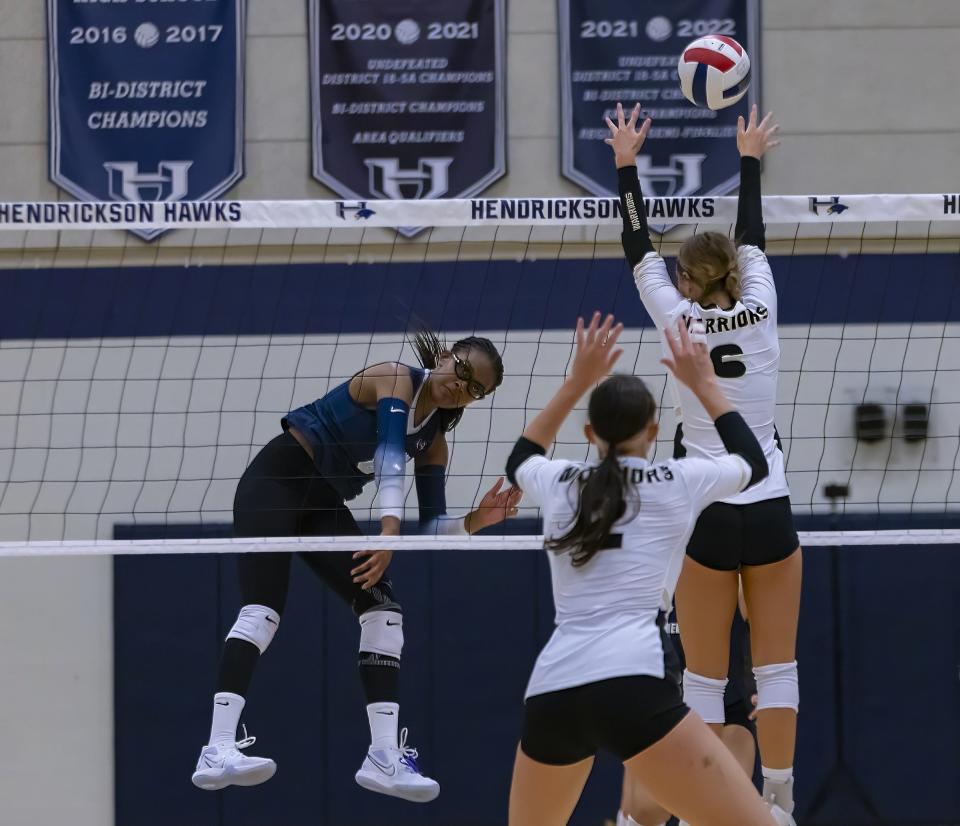 Hendrickson's Kara Wynn, left, delivers the ball over the net against Katy Jordan during the second set of the Hawks' three-set loss in the championship match of the Pflugerville VolleyPfest.