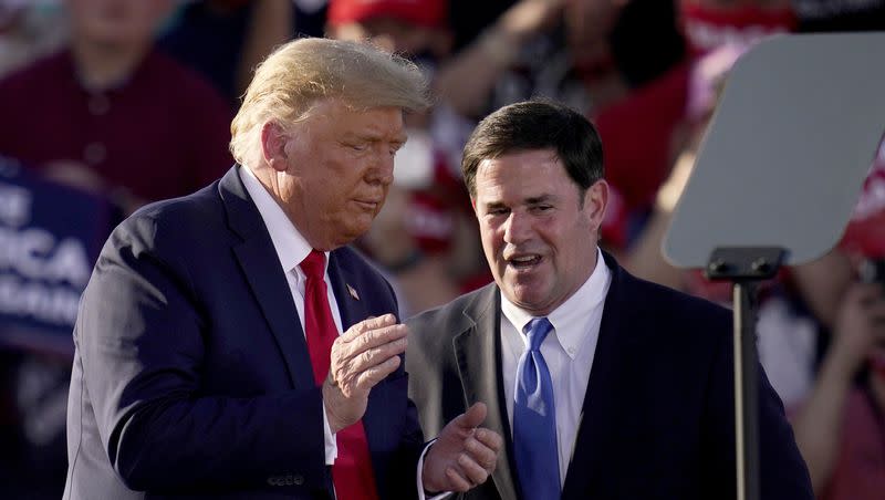 President Donald Trump, left, pauses with Arizona Gov. Doug Ducey during a campaign rally Monday, Oct. 19, 2020, in Tucson, Ariz. According to new allegations, Trump reportedly tried pressuring then-Gov. Ducey to overturn the election results in the state in 2020.