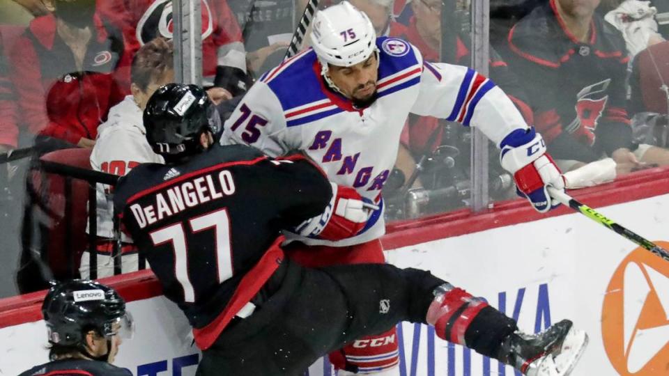 Carolina Hurricanes defenseman Tony DeAngelo (77) checks New York Rangers right wing Ryan Reaves (75) into the boards during the third period in Game 2 of an NHL hockey Stanley Cup second-round playoff series Friday, May 20, 2022, in Raleigh, N.C. (AP Photo/Chris Seward)