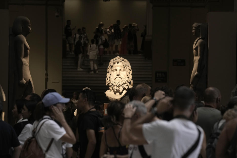 Hundreds of tourists surround the Colossal head of the god Serapis, center, one of the most important gods in the Greek and Roman periods, at the Egyptian museum in Cairo, Egypt, Wednesday, Sept. 27, 2023. The country is aiming at reaching 30 million visitors by 2028, as its once-thriving tourism sector has begun to recover from the fallout of the coronavirus pandemic and the grinding war in Europe, Egypt's Tourism and Antiquities Minister Ahmed Issa said during an interview with the Associated Press. (AP Photo/Amr Nabil)