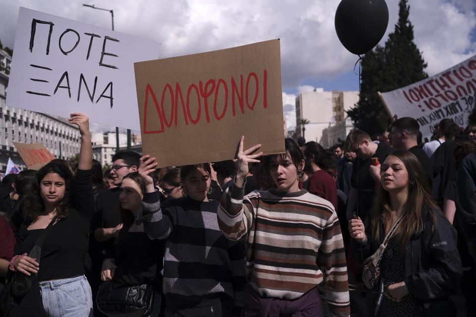 People hold placards that read "Murderers," center, and "Never again", during a protest outside the Greek parliament, in Athens, Greece, Sunday, March 5, 2023. Thousands protesters, take part in rallies around the country for fifth day, protesting the conditions that led the deaths of dozens of people late Tuesday, in Greece's worst recorded rail accident. (AP Photo/Aggelos Barai)