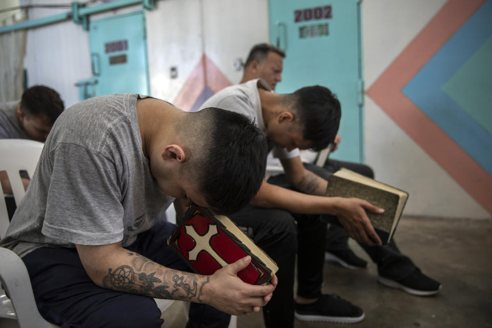 Prisoners pray with their Bibles inside an evangelical cellblock at the prison in Pinero, Santa Fe province, Argentina, Thursday, Nov. 18, 2021. Evangelical cellblocks are much like those in the rest of the prison but they are safer and calmer than the regular units. (AP Photo/Rodrigo Abd)