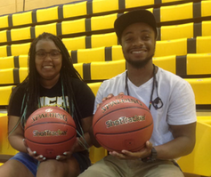 Two African American students each hold a basketball as they sit down on a bench.