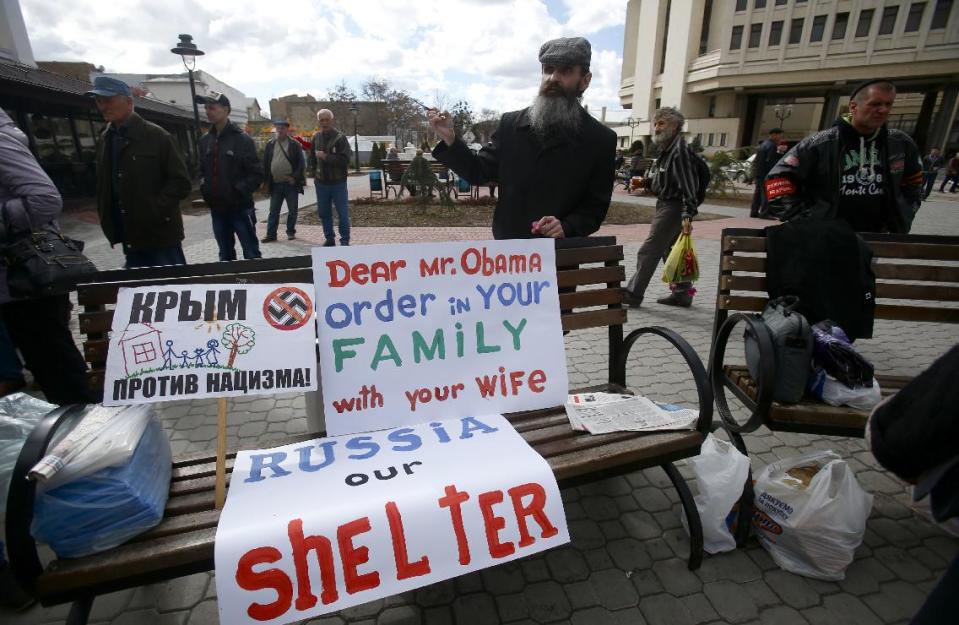 In this photo taken Wednesday, March 5, 2014, pro-russian supporters display their placards, on of them is written "Crimea is against fascism" outside local parliament in Simferopol, Ukraine. Ukraine is facing a potentially crippling geographic and cultural divide, a growing gulf between supporters of Russia who dominate the east and south of the country, and western Ukrainians who yearn for closer ties to Western Europe. One side of that divide is even starker in Crimea, a Black Sea peninsula. For much of the past 200 years, Crimea was under Russian and Soviet control, and today most Crimeans see themselves as only nominally Ukrainian and Russian is, by far, the dominant language (AP Photo/Sergei Grits)