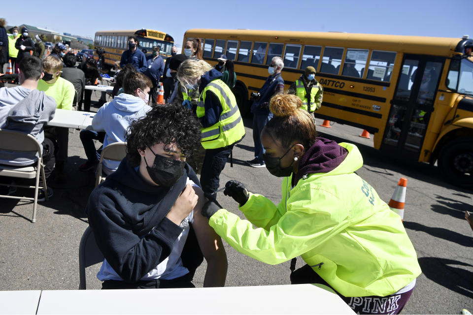 CREC Academy of Aerospace and Engineering sophmore Brian Acevedo, 16, receives a vaccination from LPN Myra Glass of East Hartford at a mass vaccination site at Pratt & Whitney Runway in East Hartford, Conn., Monday, April 26, 2021. Community Health Center, Inc. (CHC) hosted a "student skip day" to administer the first dose of the Pfizer vaccine to students from East Hartford High School and CREC Schools at the mass vaccination site. (AP Photo/Jessica Hill)