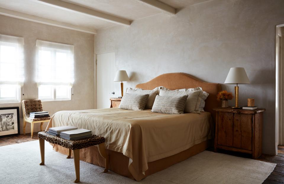 The master bedroom features a Hästens bed with Frette linens and a headboard covered in a linen by Anne Kirk Textiles. Vintage chair, stool, and table lamps by Marc Du Plantier.