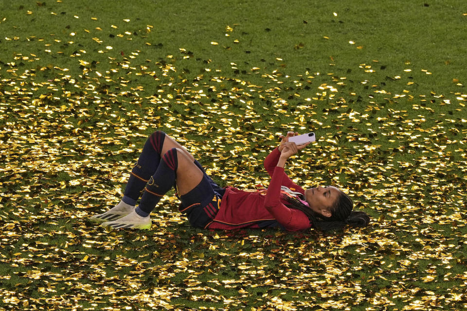 Spain's Salma Paralluelo uses her mobile phone as she lies among the glitters after her team's victory at the Women's World Cup soccer final against England at Stadium Australia in Sydney, Australia, Sunday, Aug. 20, 2023. (AP Photo/Mark Baker)