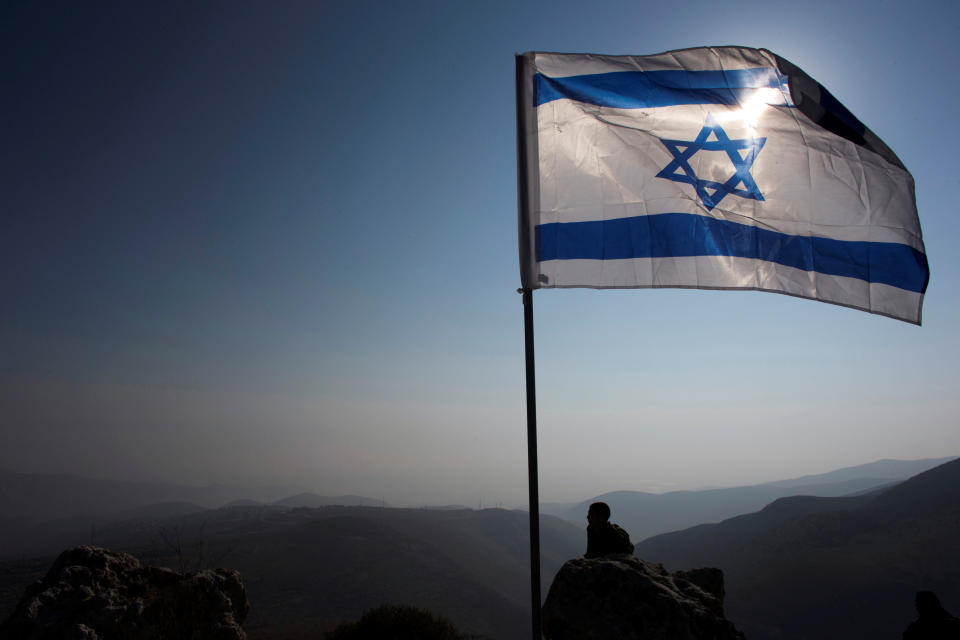 FILE PHOTO: Israeli soldier stands guard under an Israeli national flag in the Jordan Valley