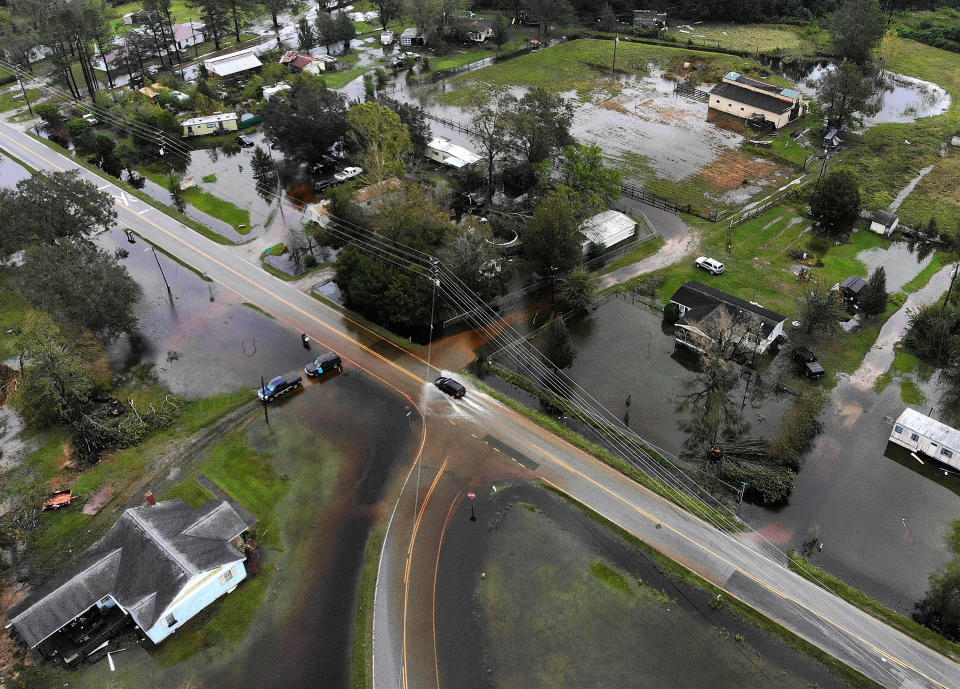 A car drives down a flooded road in Leland, North Carolina.