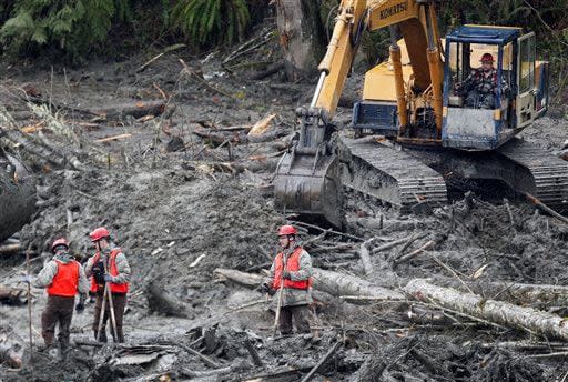 Workers continue to dig through debris on foot and by excavator at the west side of the mudslide on Highway 530 near mile marker 37 on Sunday, March 30, 2014, in Arlington, Wash. Periods of rain and wind have hampered efforts the past two days, with some rain showers continuing today. (AP Photo/Rick Wilking, Pool)