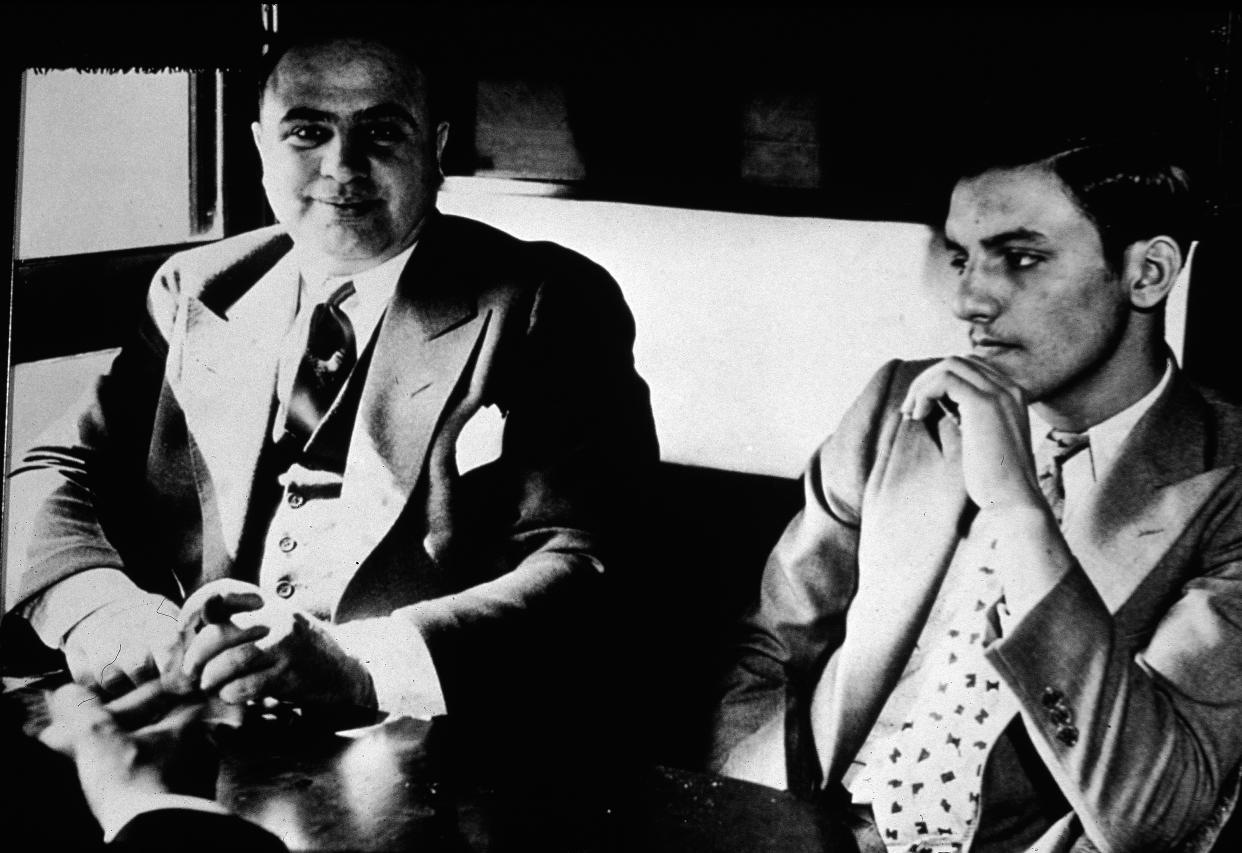Al Capone (left) sits in a train compartment with an unidentified associate during his transport to prison in October 1931. / Credit: Hulton Archive/Getty Images