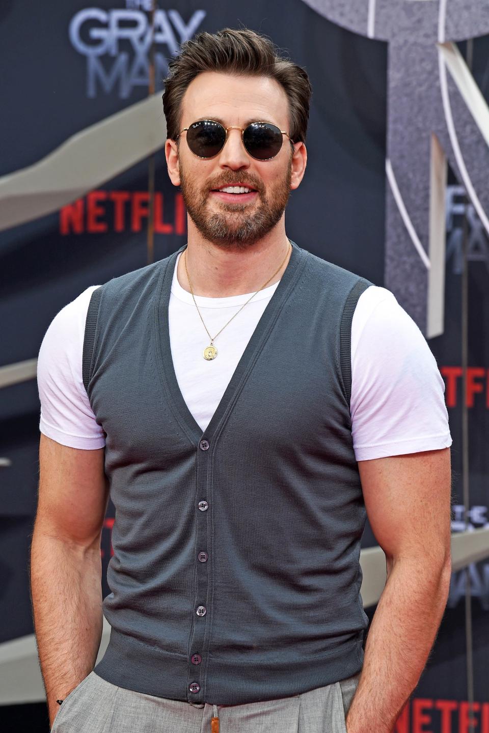 Chris in a vest over a T-shirt, with sunglasses, poses at a Netflix event